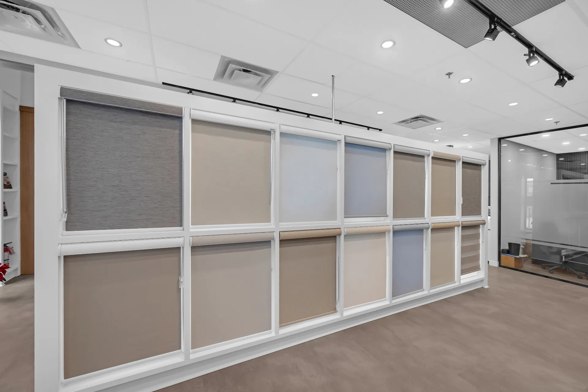 Alpine's Calgary showroom — a full wall of roller and zebra shade samples in warm neutral tones