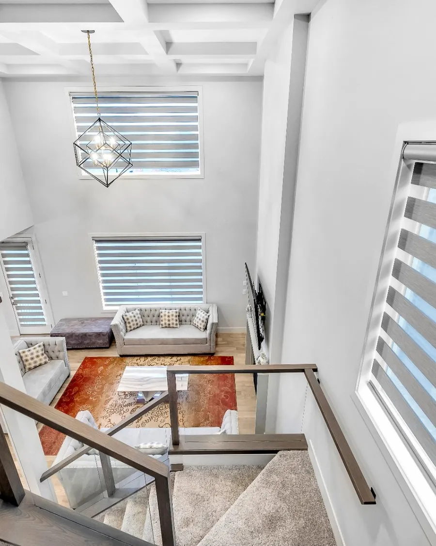 Calgary home with zebra shades on tall stairwell windows, sheer bands softening the daylight